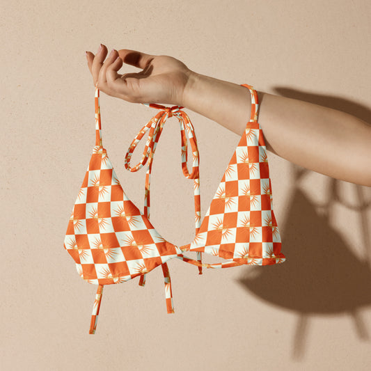 Turn heads with vibrant summer style.
The White &amp; Orange Checked Bikini String Top from FreelivdMafiia blends playful pattern with functional design. Adjustable string ties at the neck and back give you a customizable fit, while the fresh checked print pops against sun-kissed skin. Perfect for beach days, pool parties, or reckless water escapades.